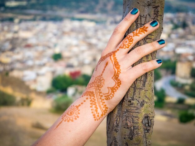 Female's hand with a henna tattoo holding a tree with the beautiful cityscape