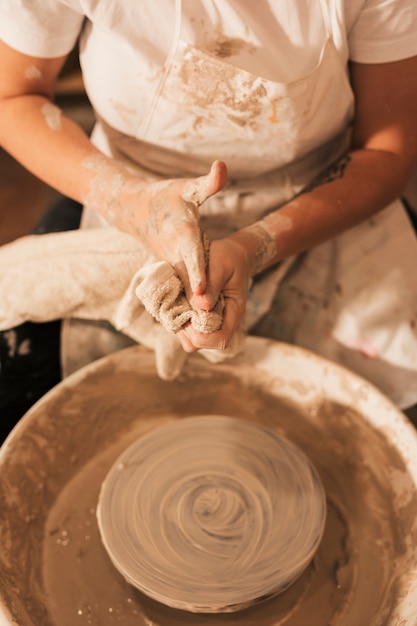 ナプキンで彼女の手を掃除する陶器のホイールの近くに座っている女性の陶工