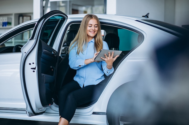 Female salesperson at a car showroom by the car