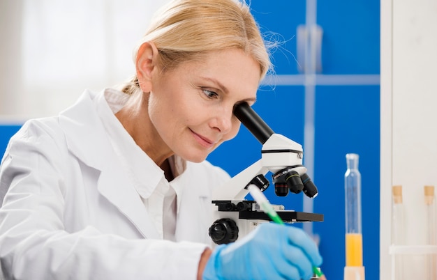 Женский ученый, анализ с помощью микроскопа в лаборатории