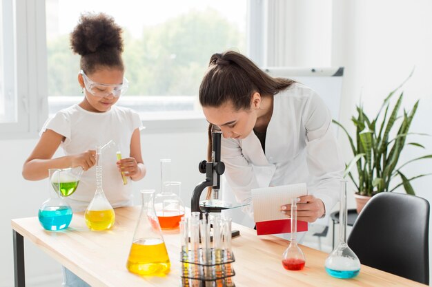 女の子と試験管で顕微鏡をのぞいて女性科学者