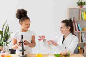 Free photo female scientist teaching chemistry to young girl