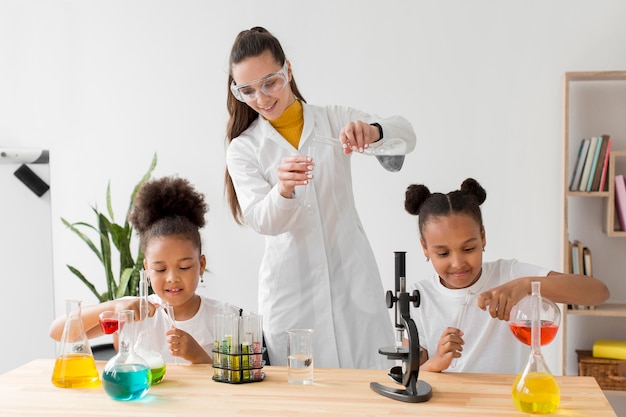 Женщина-ученый обучает девочек химическим экспериментам