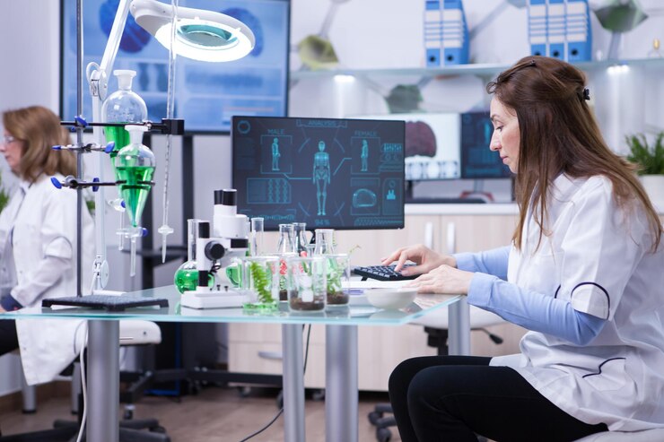 無料Photo 前回の科学的テストのデータを自分のコンピューターに入力している女性科学者。化学実験室。