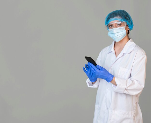 Female scientist with safety glasses and hair net holding smartphone
