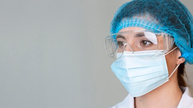 Female scientist with safety glasses, hair net and medical mask