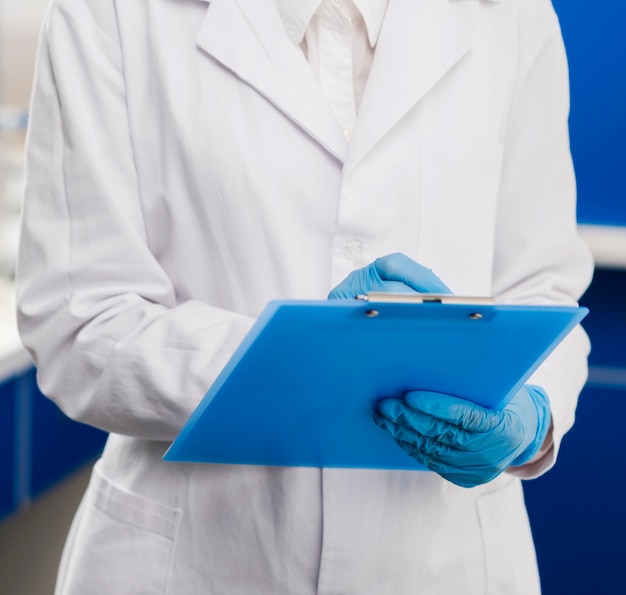 Женский ученый с хирургические перчатки, что-то писать на блокноте
