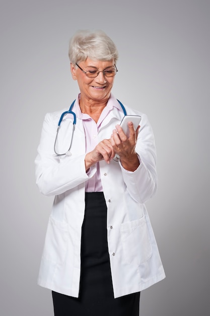 Female senior doctor with smart phone