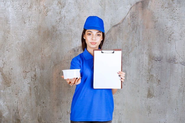 Female service agent in blue uniform holding a plastic bowl and asking for a signature