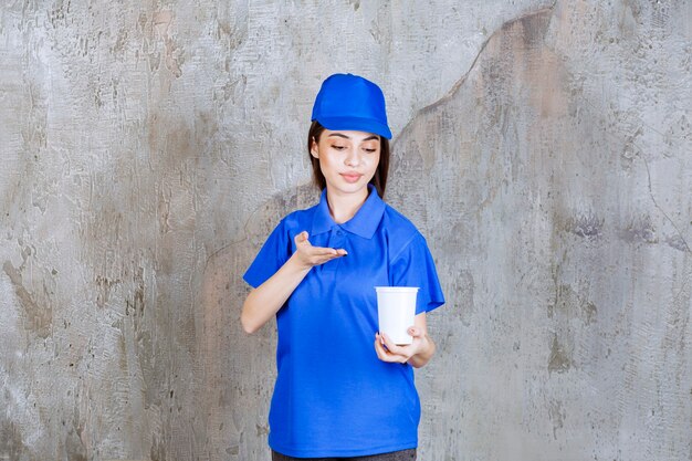 Female service agent in blue uniform holding a white disposable cup.