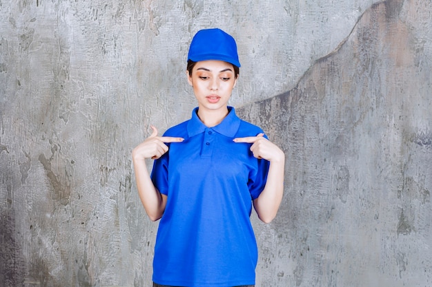 Foto gratuita agente di servizio femminile in uniforme blu che indica se stessa.