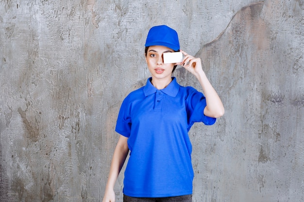 Foto gratuita agente di servizio femminile in uniforme blu che presenta il suo biglietto da visita.