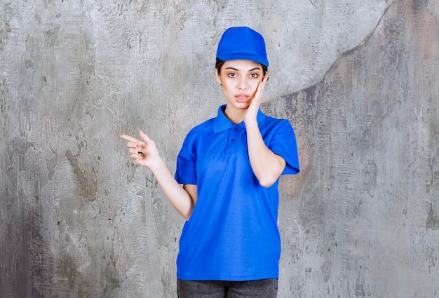 Agente di servizio femminile in uniforme blu che mostra a sinistra.