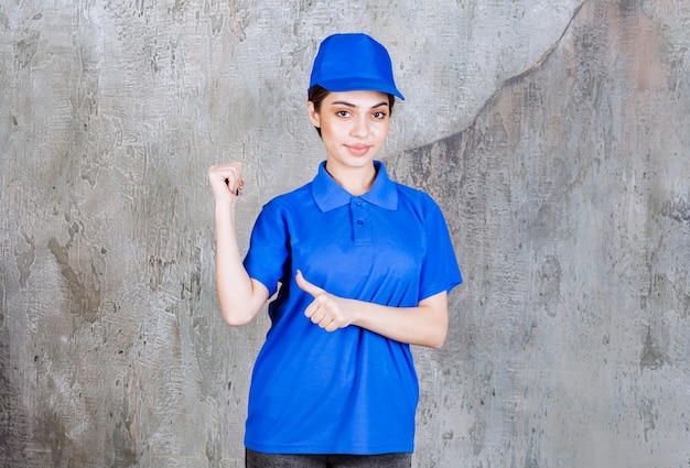 Female service agent in blue uniform showing something behind.