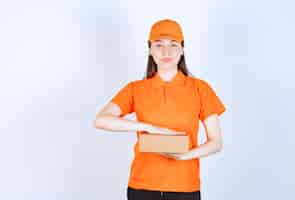 Foto gratuita agente di servizio femminile in dresscode di colore arancione con in mano una scatola di cartone