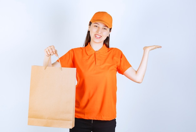 Female service agent in orange color dresscode holding a cardboard shopping bag