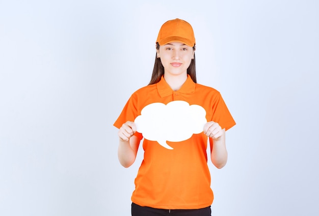 Foto gratuita agente di servizio femminile in dresscode di colore arancione che tiene una scheda informativa a forma di nuvola.