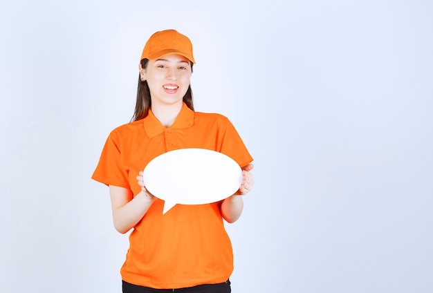 Female service agent in orange color dresscode holding an ovale info board.