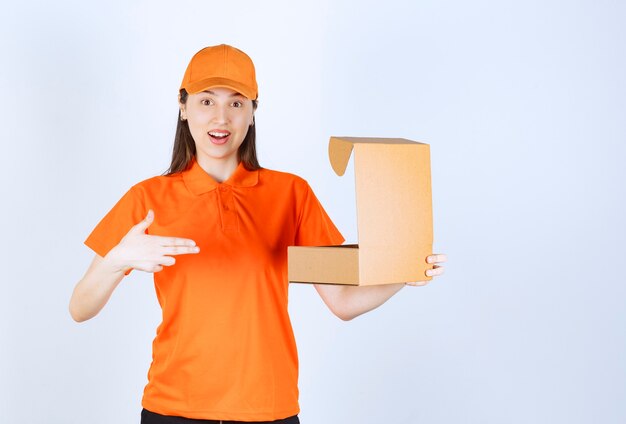 Female service agent in orange color uniform holding an open cardboard box.