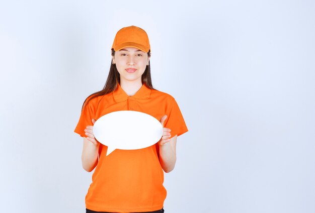 Female service agent in orange color uniform holding an ovale info board.