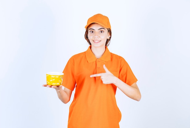 黄色のテイクアウトカップを保持しているオレンジ色の制服を着た女性サービスエージェント