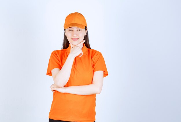 Female service agent wearing orange color dresscode and looks thoughtful