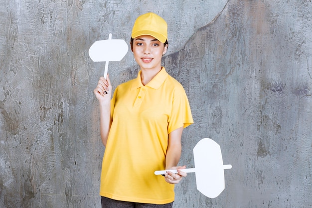 Foto gratuita agente di servizio femminile in uniforme gialla che tiene i banchi informazioni in entrambe le mani.