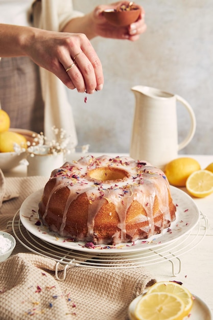 Female serving a delicious citron cake with glaze on top on a white table