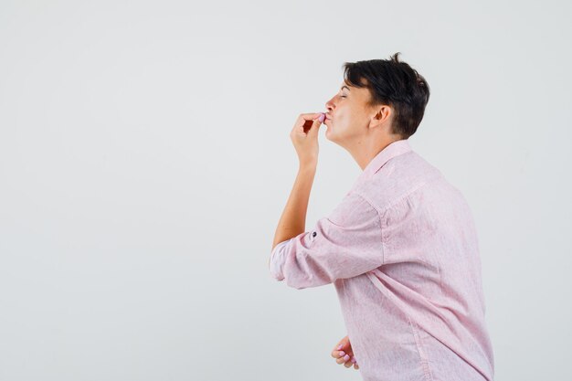 Female showing delicious gesture in pink shirt and looking delighted .