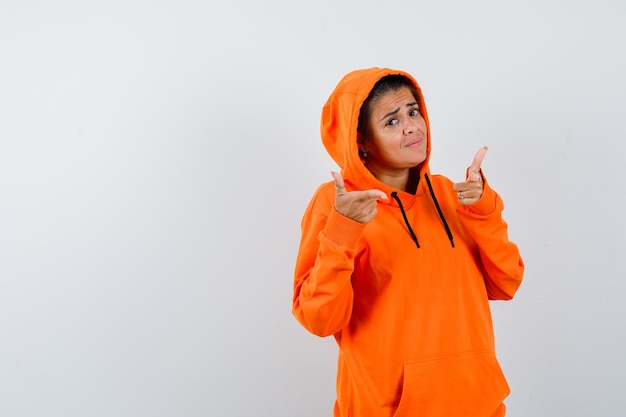 Female showing gun gesture in orange hoodie and looking confident