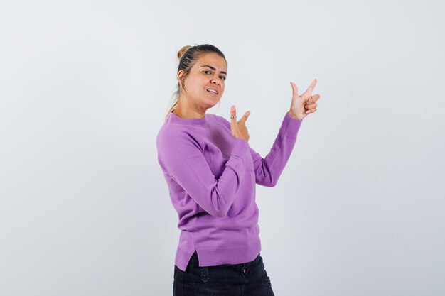 Female showing gun gesture in wool blouse and looking confident 