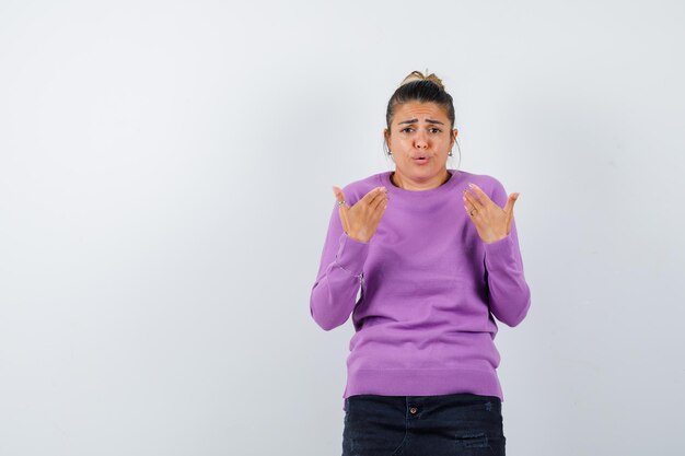 Female showing herself in questioning manner in wool blouse and looking confused 