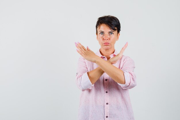 Female showing refusal gesture in pink shirt and looking anxious. front view.