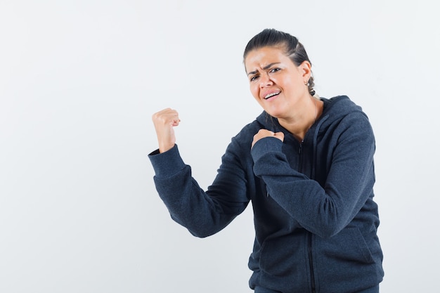 Free photo female showing winner gesture in hoodie and looking blissful. front view.