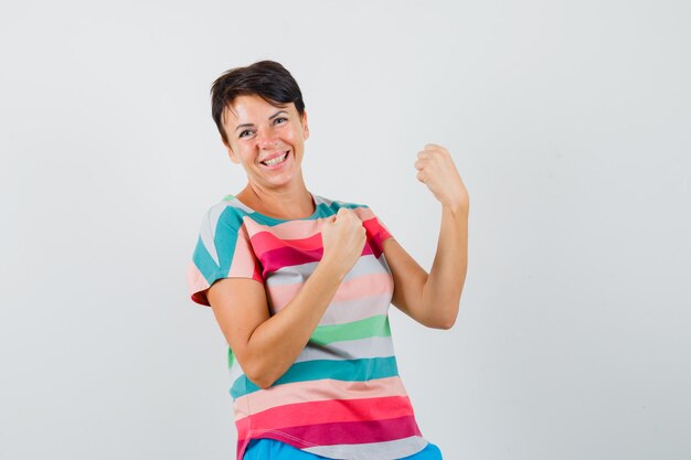 Female showing winner gesture in striped t-shirt and looking blissful. front view.