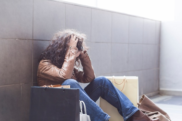 Female sitting on ground with shopping bags