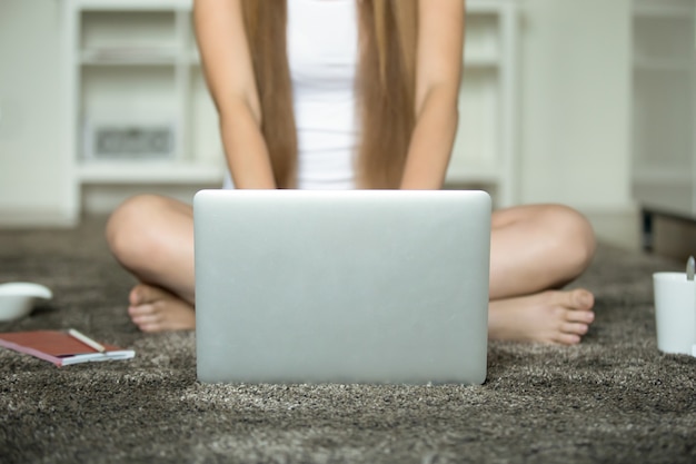 Free photo female sitting legs crossed at the floor, laptop in front