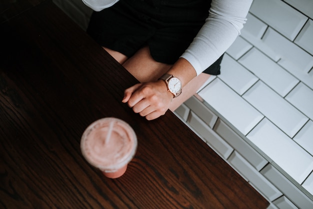 Free photo female sitting on a white decorative brick bench with a strawberry milkshake next to her