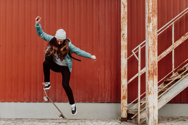 Бесплатное фото Фигуристка, практикующая скейтбординг на открытом воздухе
