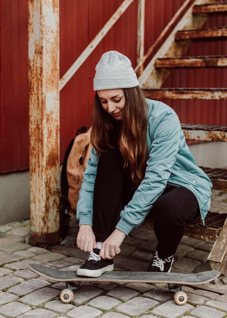 Female skater sitting next to her skateboarding outdoors