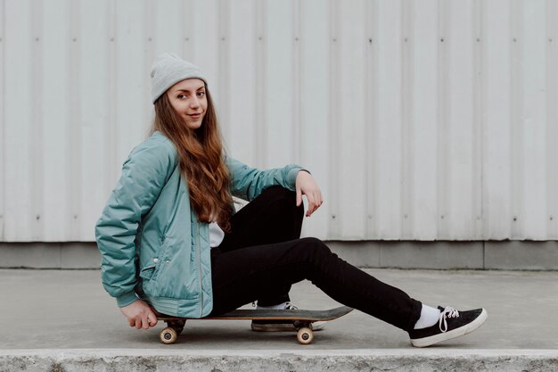 屋外でスケートボーディングの隣に座っている女性スケーター