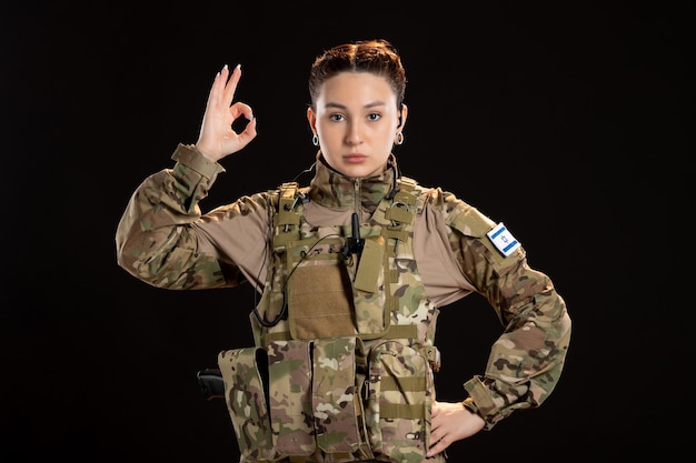 黒い壁に迷彩を着た女性兵士