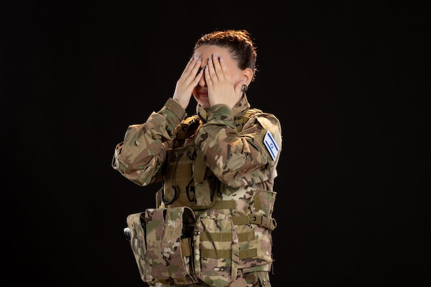 Female soldier in camouflage on black wall