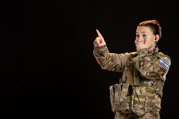 Female soldier in camouflage on black wall