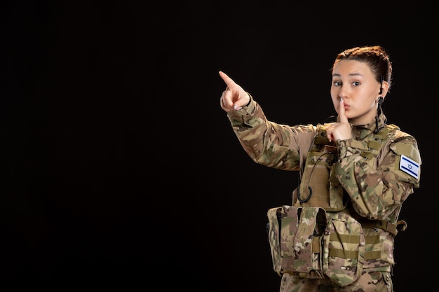 Female soldier in camouflage on black wall