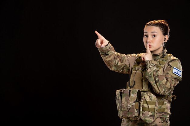 Female soldier in camouflage on black wall