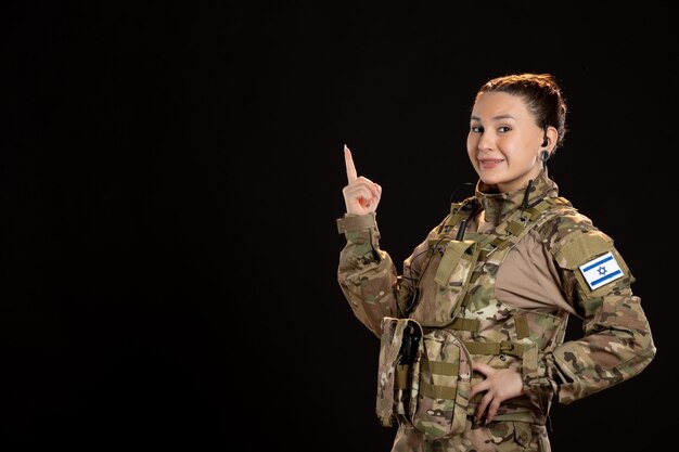 Female soldier in camouflage on black wall