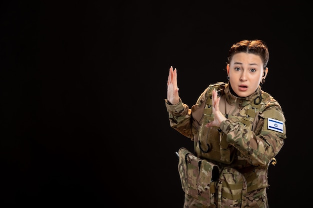 Female soldier in camouflage on black wall