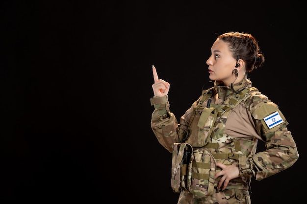 Female soldier in camouflage on black wall