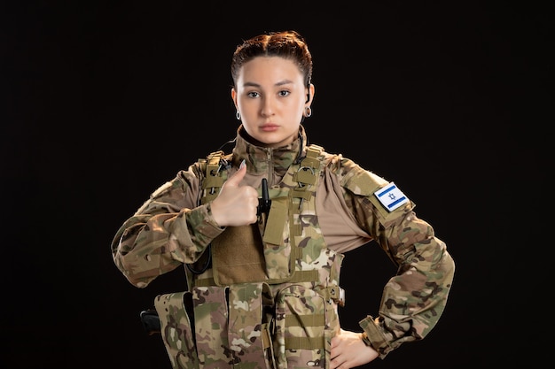 Female soldier in camouflage on black wall